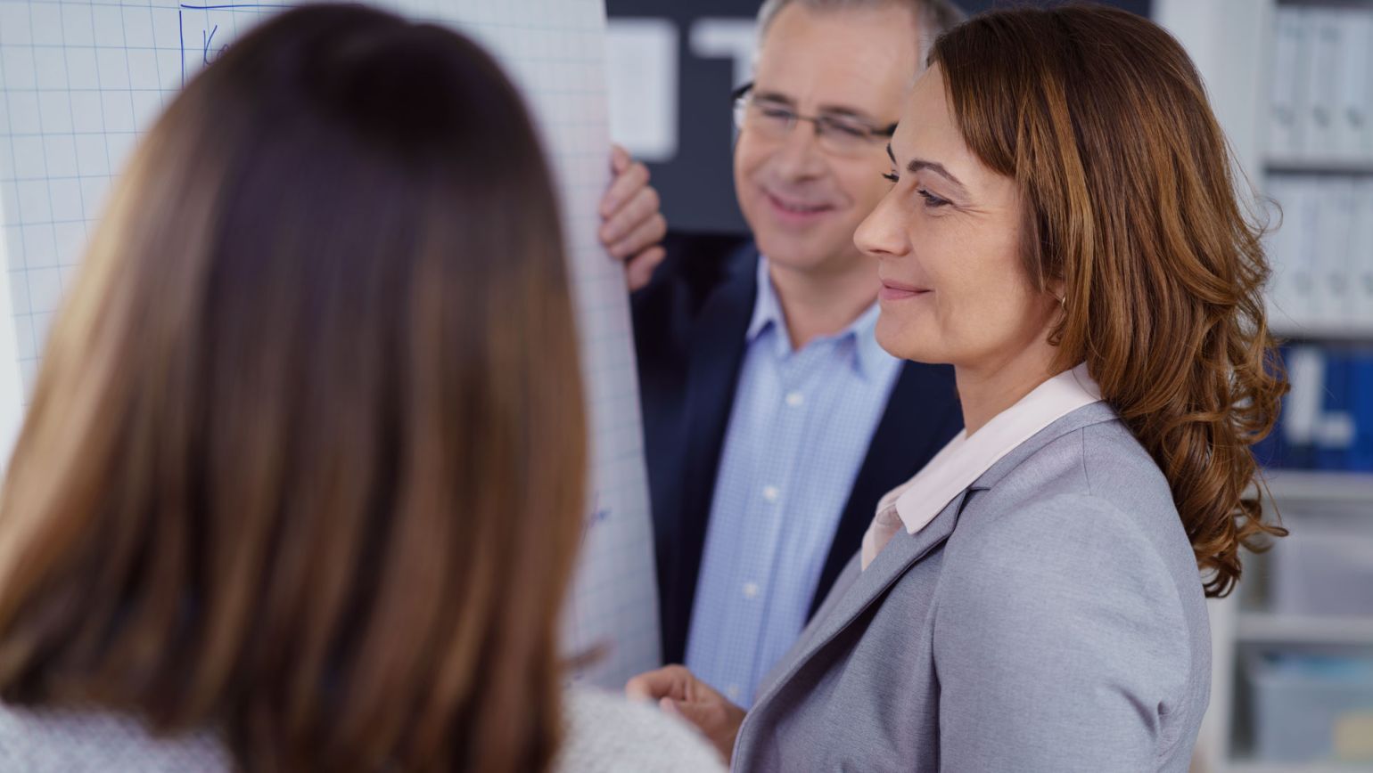 Seitliche Nahaufnahme eines professionellen Gesprächs vor einem Flipchart: Eine Auditorin im Fokus, im Hintergrund ein Kollege, im Vordergrund unscharf eine Teilnehmerin. Das Motiv steht für unabhängige Inspektion, Compliance und Auditbereitschaft in regulierten, sicherheitskritischen Branchen. Seitliche Nahaufnahme eines professionellen Gesprächs vor einem Flipchart: Eine Auditorin im Fokus, im Hintergrund ein Kollege, im Vordergrund unscharf eine Teilnehmerin. Das Motiv steht für unabhängige Inspektion, Compliance und Auditbereitschaft in regulierten, sicherheitskritischen Branchen.